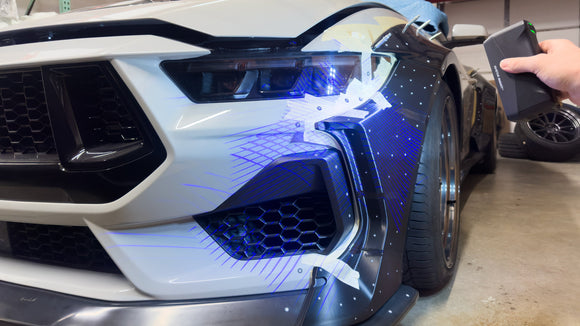 Einstar Rockit handheld 3D scanner projecting blue laser lines onto a Clinched widebody fender on an S650 Mustang